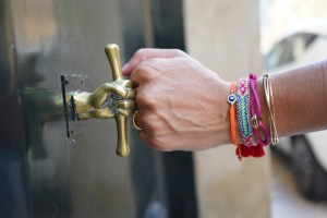 Person wearing bracelets giving a fist bump to a door handle shaped like a fist