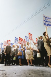 Racial equality march with a racially diverse group of people marching and holding signs. Undated but appears to be 1960s.