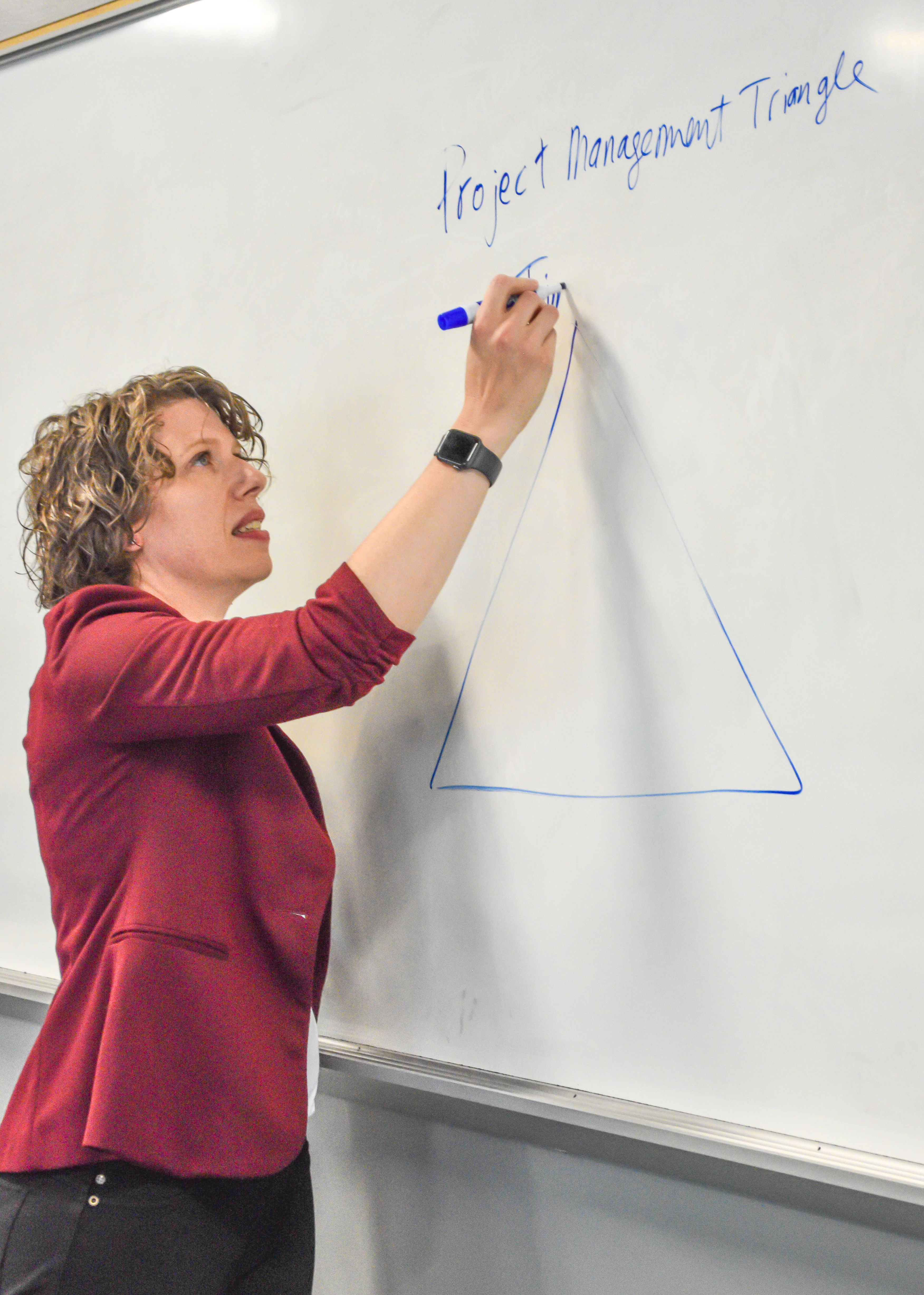 Hannah Grannemann teaching at a white board wearing a red blazer.