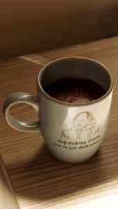 coffee mug with quote "stop making drama, you're not shakespeare" on wooden surface